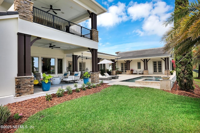 rear view of house featuring outdoor lounge area, a balcony, french doors, a ceiling fan, and a lawn