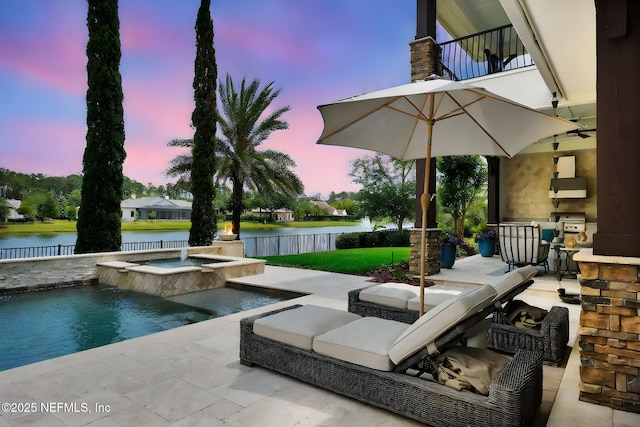 view of patio with a fenced backyard, a water view, a pool with connected hot tub, and a balcony