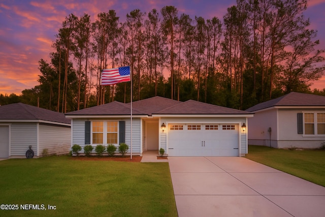 ranch-style house featuring a garage, concrete driveway, and a yard