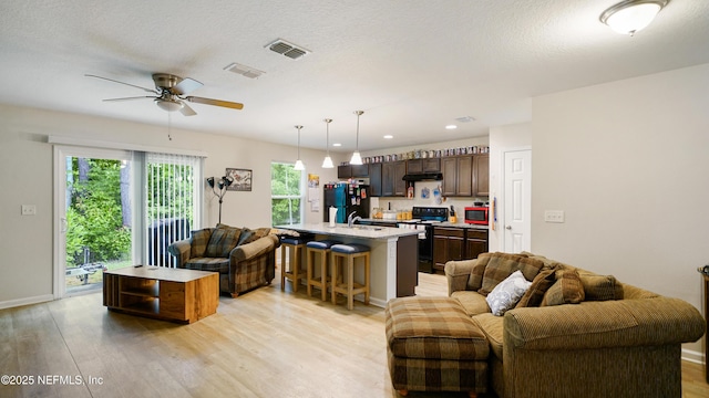 living area with a ceiling fan, recessed lighting, light wood-style flooring, and visible vents