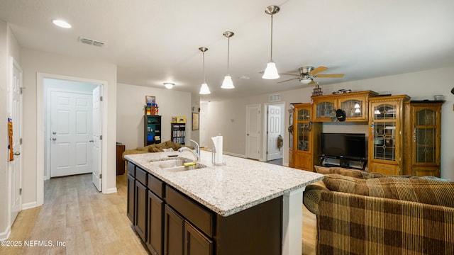 kitchen featuring a ceiling fan, visible vents, a sink, open floor plan, and light wood-style floors