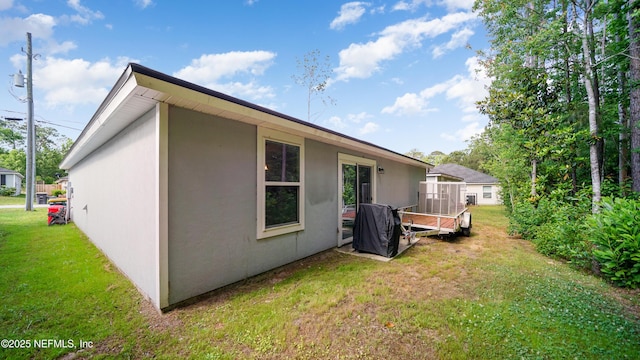 back of property with stucco siding, a yard, and a wooden deck