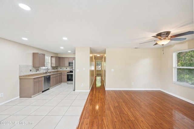 kitchen featuring a sink, light wood-style floors, light countertops, plenty of natural light, and stainless steel appliances