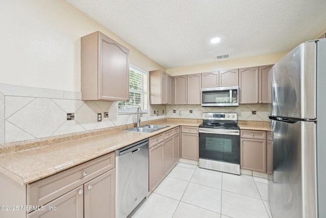 kitchen featuring visible vents, decorative backsplash, light countertops, a sink, and stainless steel appliances