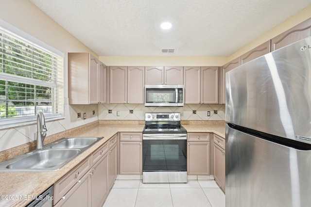 kitchen featuring decorative backsplash, visible vents, appliances with stainless steel finishes, a sink, and light countertops