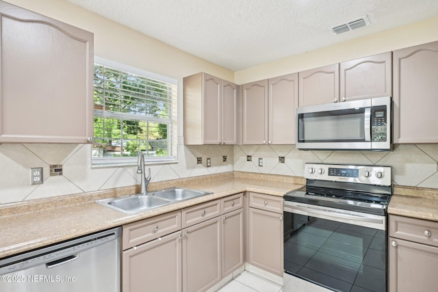 kitchen with visible vents, light countertops, a sink, backsplash, and stainless steel appliances