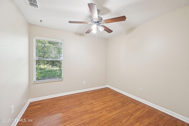 empty room featuring visible vents, baseboards, ceiling fan, and wood finished floors