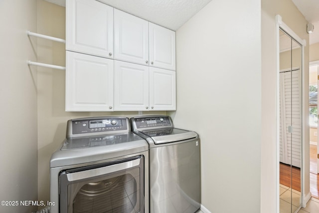 washroom with light tile patterned floors, baseboards, independent washer and dryer, and cabinet space