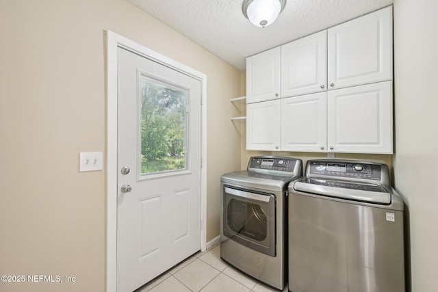 laundry room featuring cabinet space, washer and dryer, a textured ceiling, baseboards, and light tile patterned floors