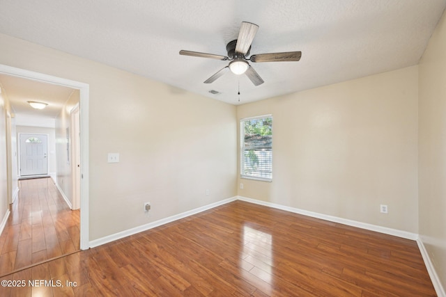 empty room with wood-type flooring, baseboards, visible vents, and ceiling fan