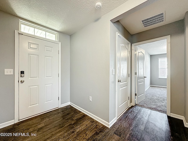 entrance foyer with a textured ceiling, visible vents, dark wood-style floors, and a healthy amount of sunlight