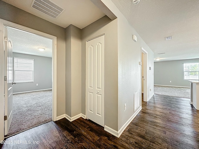 hallway with baseboards, visible vents, and dark wood-type flooring