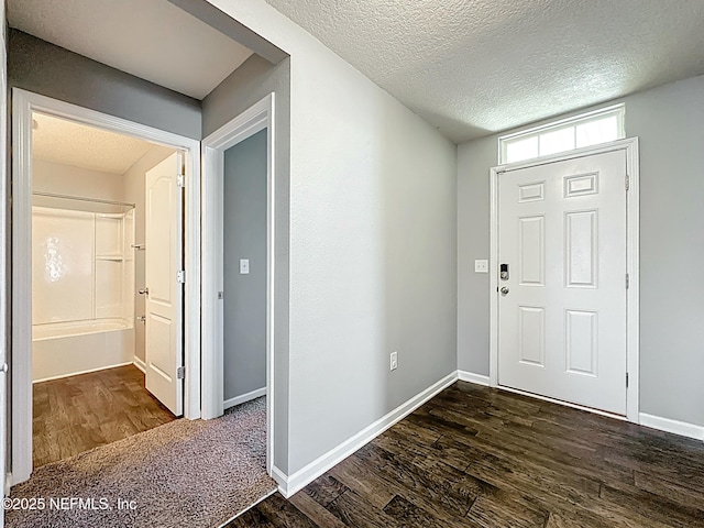 entrance foyer featuring dark wood finished floors, a textured ceiling, and baseboards