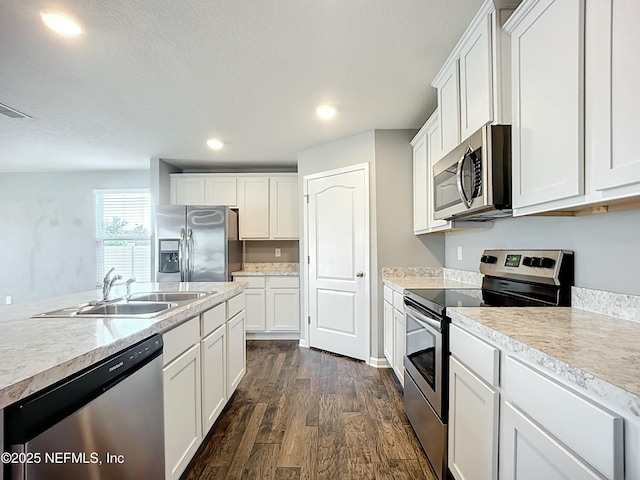 kitchen with dark wood finished floors, stainless steel appliances, white cabinets, and a sink