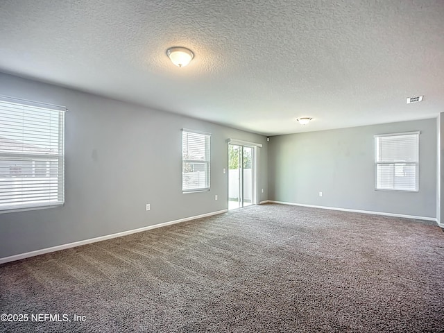 carpeted spare room with baseboards, visible vents, and a textured ceiling