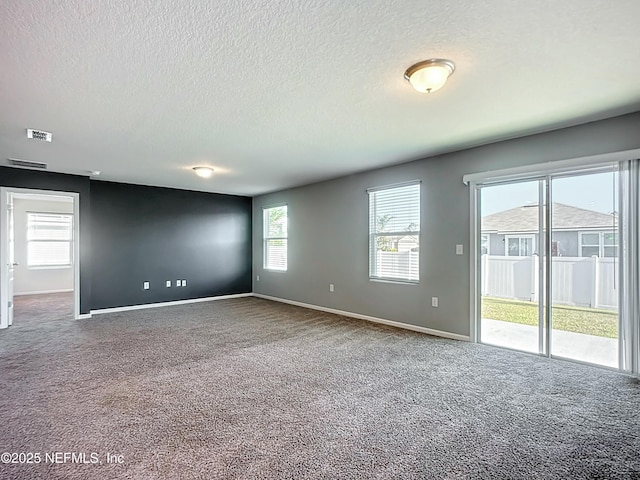 unfurnished room featuring a textured ceiling, carpet floors, visible vents, and baseboards
