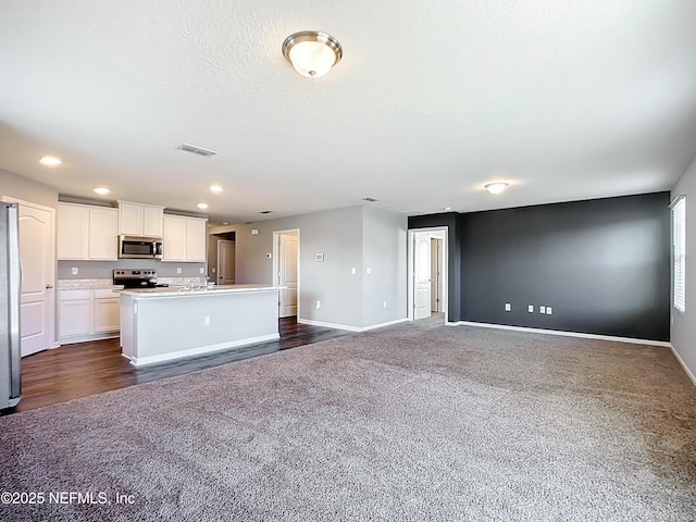 kitchen featuring white cabinets, dark colored carpet, baseboards, and appliances with stainless steel finishes