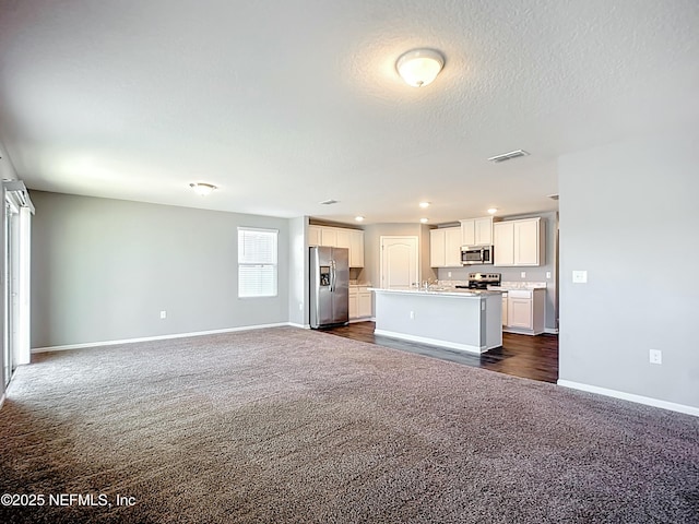 kitchen with stainless steel appliances, dark carpet, visible vents, baseboards, and open floor plan