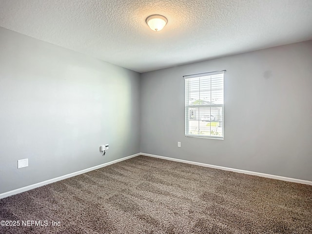 carpeted spare room featuring a textured ceiling and baseboards