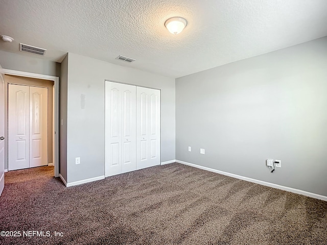 unfurnished bedroom with a textured ceiling, visible vents, and baseboards
