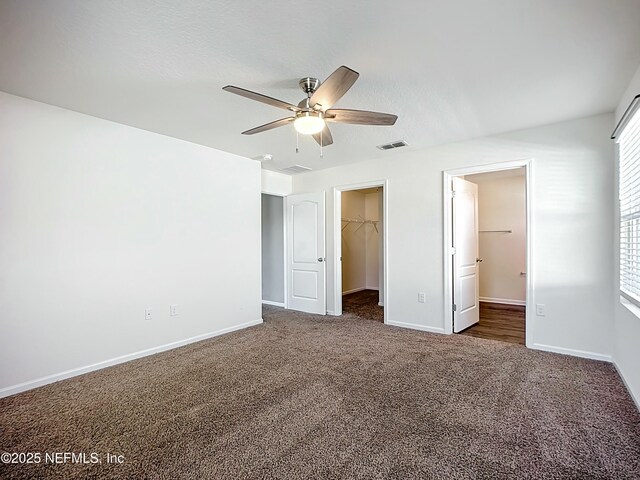 unfurnished bedroom featuring baseboards, a spacious closet, visible vents, a closet, and carpet floors