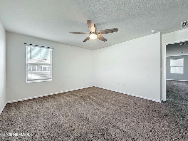 empty room featuring a ceiling fan, baseboards, dark carpet, and a textured ceiling