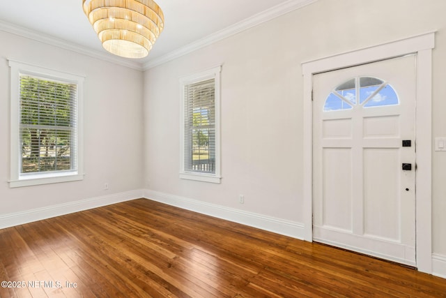 entrance foyer featuring crown molding, baseboards, an inviting chandelier, and hardwood / wood-style floors