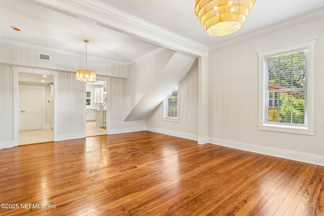 interior space with a wealth of natural light, ornamental molding, hardwood / wood-style floors, and a notable chandelier