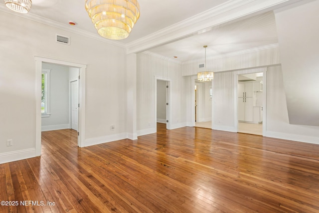 interior space featuring crown molding, an inviting chandelier, hardwood / wood-style floors, baseboards, and visible vents