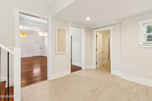 empty room with stairs, baseboards, a notable chandelier, and wood finished floors