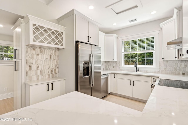 kitchen featuring backsplash, stainless steel appliances, light stone counters, and a sink