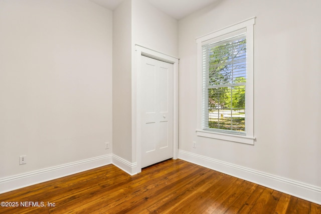 spare room with a healthy amount of sunlight, baseboards, and dark wood-style flooring