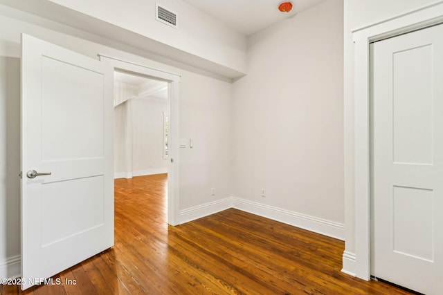 spare room with baseboards, dark wood-style floors, and visible vents