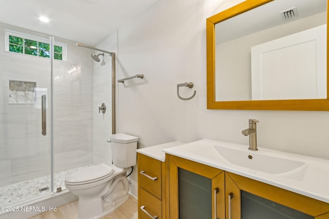 bathroom featuring vanity, toilet, a shower stall, wood finished floors, and visible vents