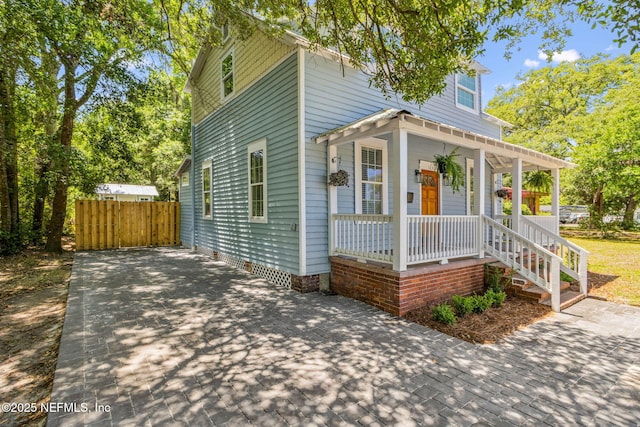 view of front facade with covered porch, fence, and driveway