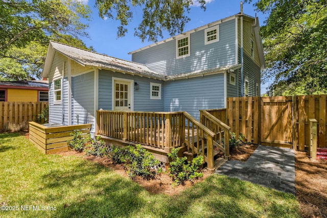 back of property featuring fence, a gate, a lawn, and a deck