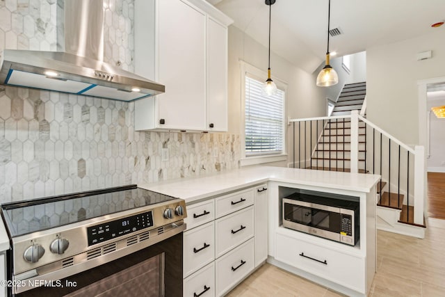 kitchen featuring wall chimney range hood, appliances with stainless steel finishes, tasteful backsplash, white cabinets, and a peninsula