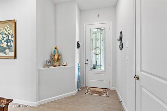 doorway with light wood finished floors and baseboards