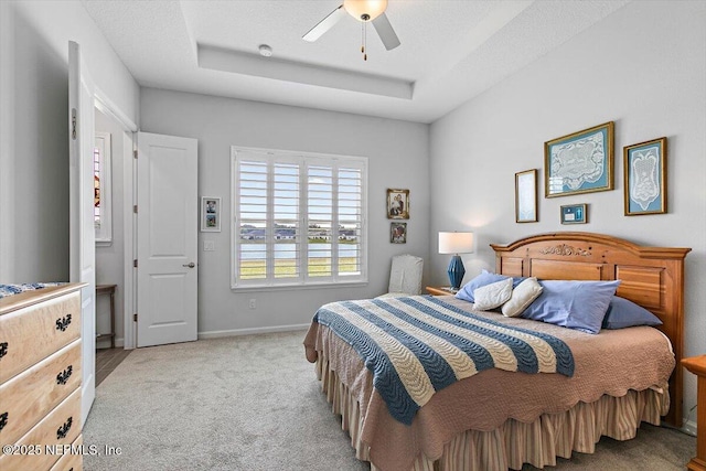 bedroom featuring a ceiling fan, carpet flooring, a raised ceiling, and baseboards