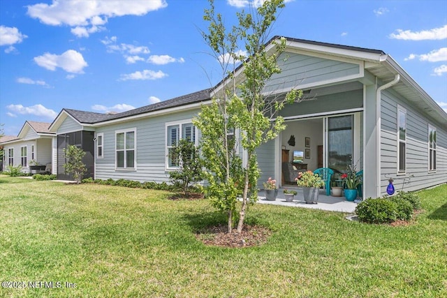 rear view of house with a lawn and a sunroom