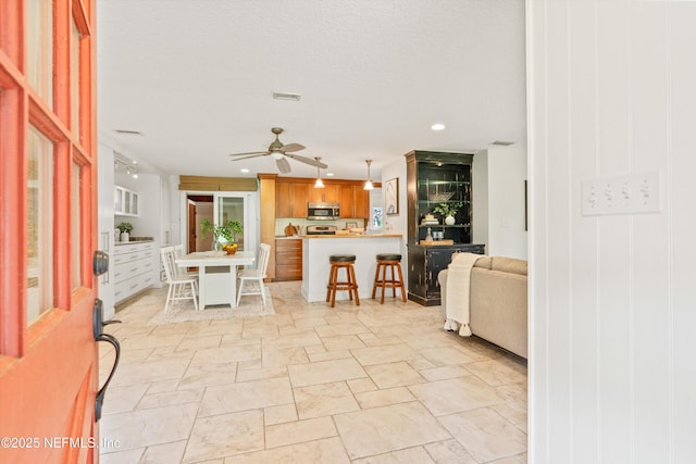 living room featuring light stone finish floors, a ceiling fan, and recessed lighting