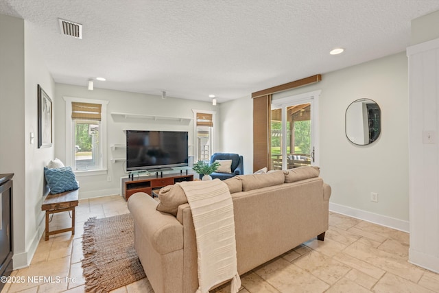 living room with plenty of natural light, a textured ceiling, baseboards, and recessed lighting