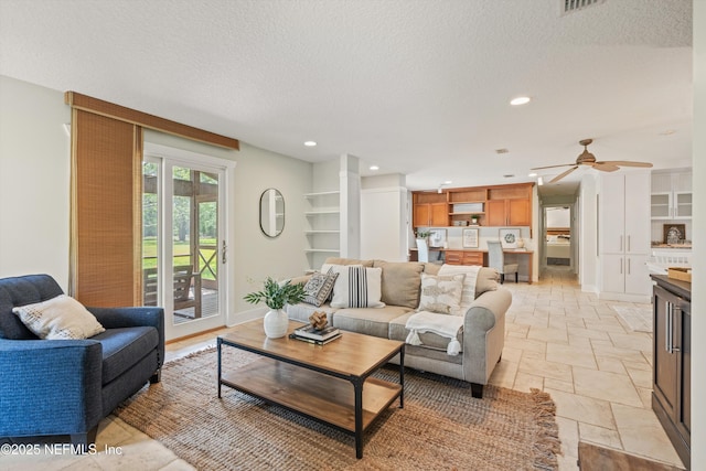 living area with stone tile floors, a textured ceiling, ceiling fan, recessed lighting, and baseboards