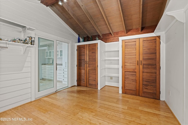 unfurnished bedroom featuring wood finished floors, access to exterior, wooden ceiling, multiple closets, and wood walls