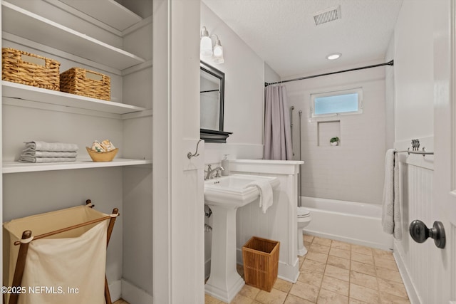 bathroom with toilet, shower / bath combination with curtain, and a textured ceiling
