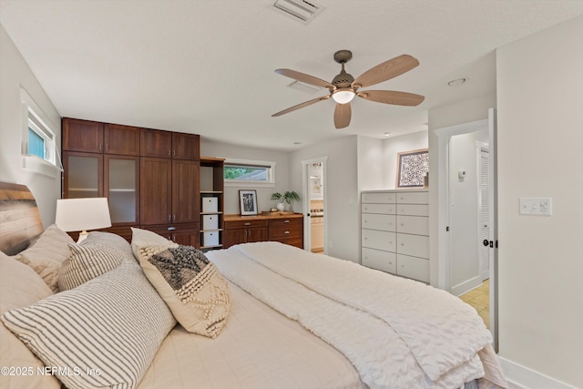 bedroom featuring baseboards, ceiling fan, and ensuite bathroom