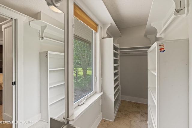 walk in closet featuring stone tile flooring