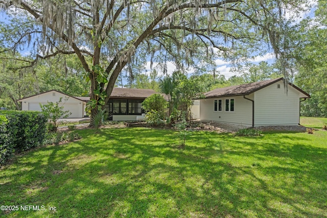 rear view of house with a garage, a yard, and a sunroom