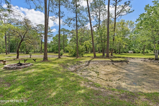 view of green lawn featuring an outdoor fire pit