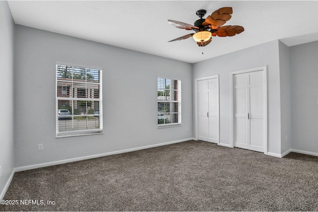unfurnished bedroom with two closets, baseboards, and carpet